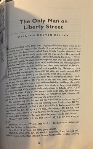 A close-up of an open book page showing the title 'The Only Man on Liberty Street' by William Melvin Kelley, with black serif text on a warm beige paper background. shows the personal note tucked into the pages.