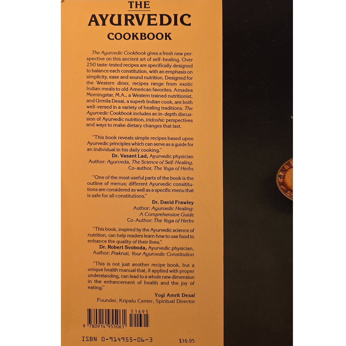 Back cover of The Ayurvedic Cookbook book, featuring a warm brown background with black text, author names, and a circular illustration of a traditional pot and ingredients on the right.