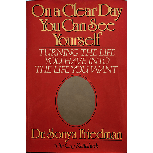 The book cover for "On a Clear Day You Can See Yourself: Turning the Life You Have into the Life You Want" by Dr. Sonya Friedman, with Guy Kettelhack, features a bold red background. The title is displayed prominently at the top in elegant, gold lettering, with the subtitle "Turning the Life You Have into the Life You Want" in white text below it. An empty oval frame is centered on the cover, symbolizing self-reflection.