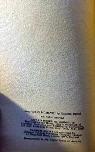 A close-up of a book's printed copyright page on textured off-white paper, with small black text near the bottom and a warm yellow cast on the right side of the page.