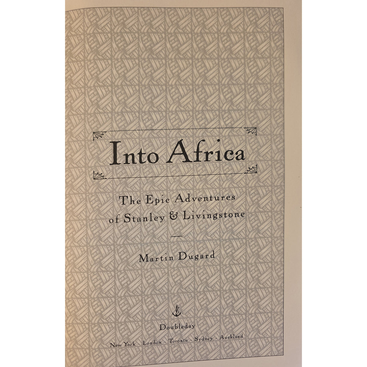 Vintage book cover for 'Into Africa: The Epic Adventures of Stanley & Livingstone' by Martin Dugard, featuring a beige and brown geometric patterned background with black serif text.