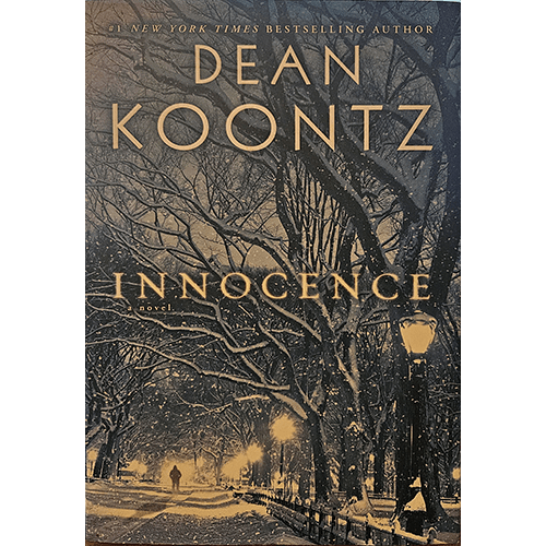 A hauntingly beautiful winter scene with a snow-dusted park path illuminated by streetlights. The golden title "Innocence" stands out amidst bare trees under a moody, dark sky.
