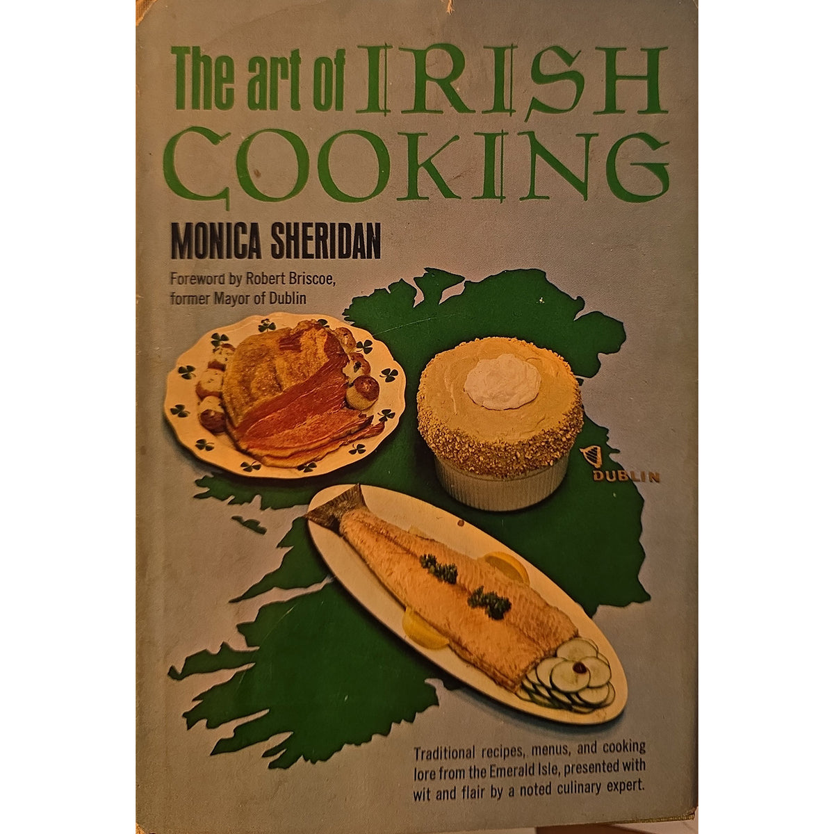 Vintage book cover for 'The art of Irish Cooking' by Monica Sheridan, featuring a beige background, green title text, a green map outline, and photos of traditional Irish dishes including a fish, a pie, and a tart.