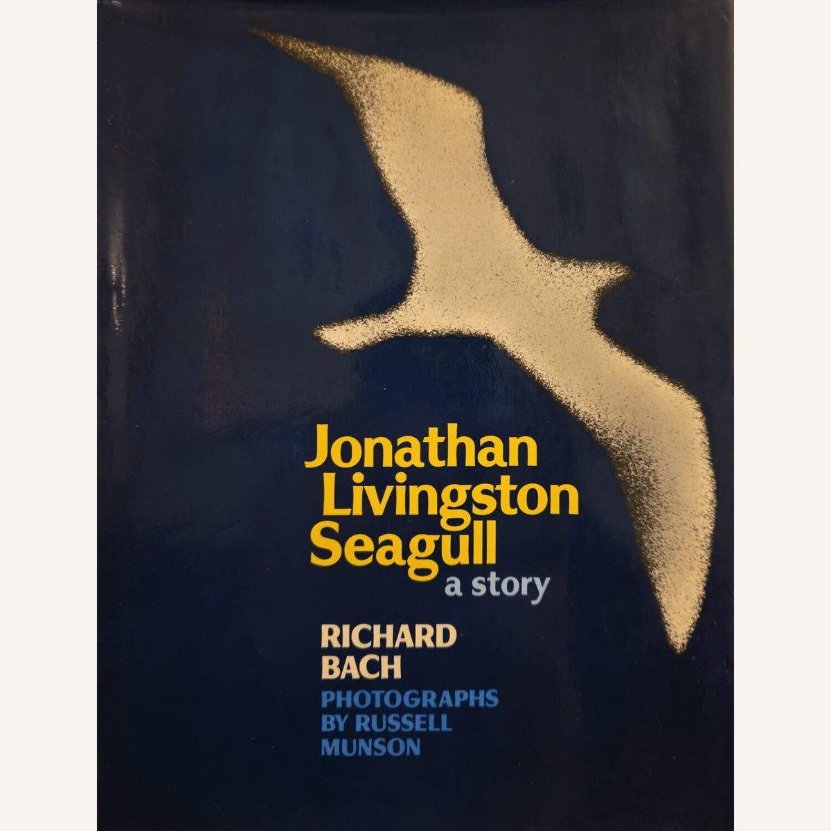 Book cover for 'Jonathan Livingston Seagull: a story' by Richard Bach, featuring a textured gold seagull silhouette on a dark navy blue background with yellow, white, and blue text.