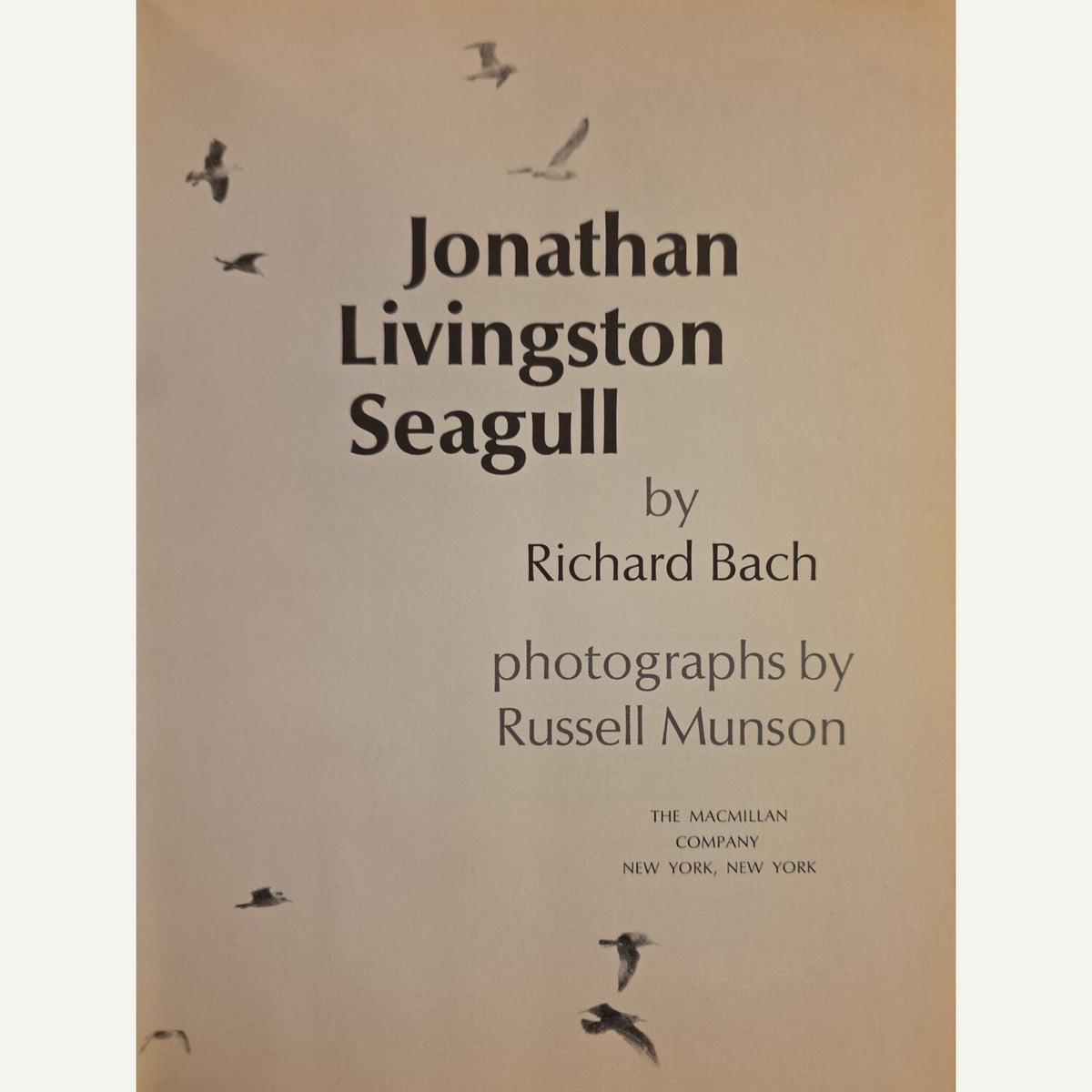 Book cover for 'Jonathan Livingston Seagull' by Richard Bach, featuring black bird silhouettes on a warm beige background with dark gray text.