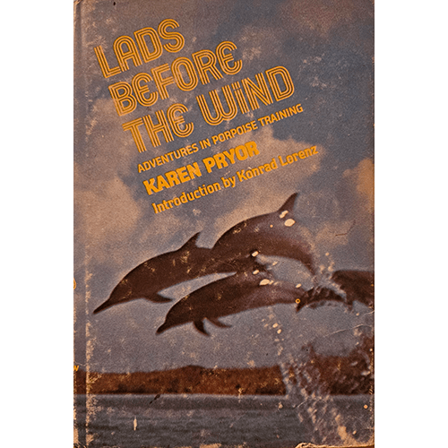 Cover of Lads Before the Wind by Karen Pryor featuring dolphins leaping from the ocean against a dusky sky.