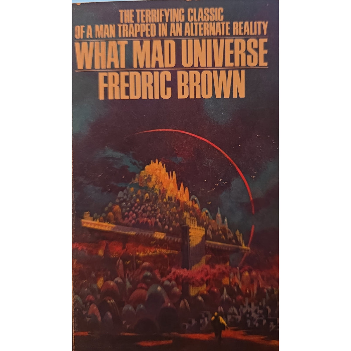 Vintage paperback book cover of 'What Mad Universe' by Fredric Brown, featuring a dark sci-fi illustration with a large pyramid-like structure, glowing orange title text, and a red curved line against a starry sky.