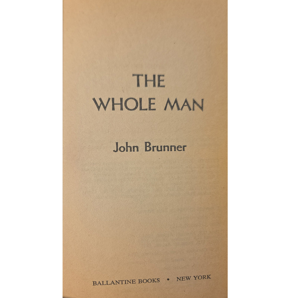 The halfcover of the book 'The Whole Man' by John Brunner, published by Ballantine Books. The cover is a warm tan or light brown color with the title and author name printed in a dark gray serif font.