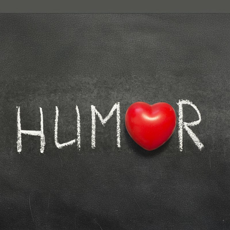  The word "Humor" written in white chalk on a blackboard, with a red heart symbol replacing the letter "O."