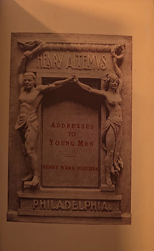 A rectangular stone relief plaque mounted on a wall, featuring two draped male figures supporting a central panel with the text 'HENRY ALFREDS' at the top and 'PHILADELPHIA' at the bottom. The center panel reads 'ADDRESSES TO YOUNG MEN' and includes 'HENRY WARD BEECHER.