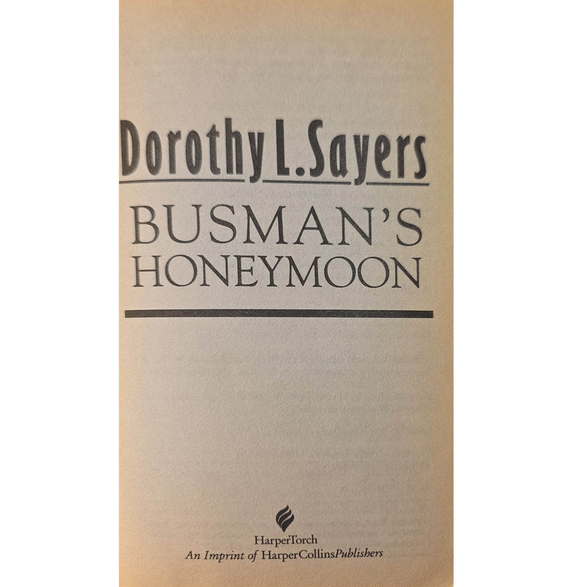 Book have title of 'Busman's Honeymoon' by Dorothy L. Sayers, published by Harper&CollinsPublishers, featuring black text on a warm beige background.