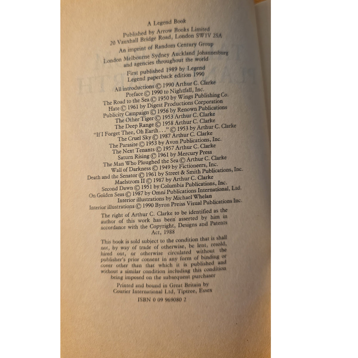 A close-up of an open book showing printed copyright and publication information on the left page, with the right page blank and warm light filtering through.
