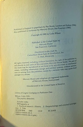 A scanned book page showing publication details for 'The psychic detective' by Colin Wilson, published by Mercury House. The page is printed on aged, yellowed paper with black text and is photographed with a soft shadow on the left side.