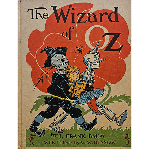 1956 edition of The Wizard of Oz by L. Frank Baum. Cover shows Dorothy, Scarecrow, and Tin Man on a vibrant red background. Illustrated by W.W. Denslow, this vintage edition is in very good condition.