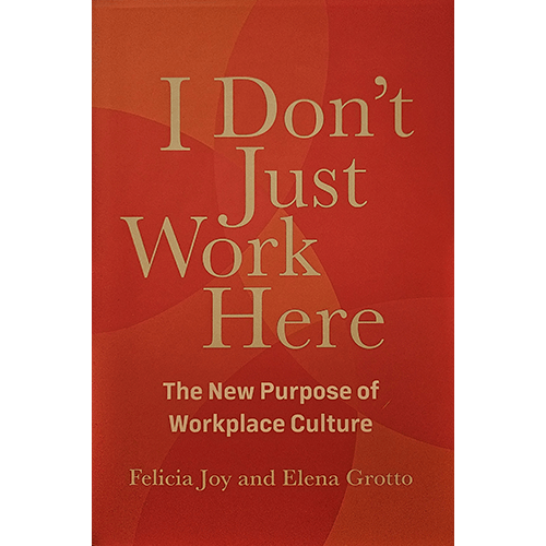 The cover of "I Don’t Just Work Here" features bold, golden text on a vibrant orange-red background, symbolizing energy and purpose. It highlights workplace culture and meaningful professional connection.