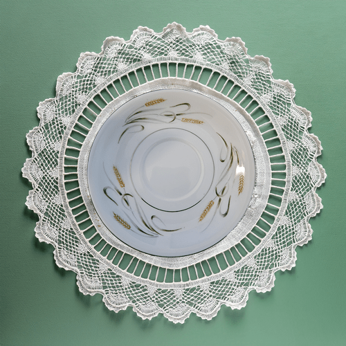 Decorative white lace doily on a green background