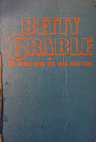 Front cover of 1944 Whitman authorized edition “Betty Grable and the House With the Iron Shutters” in green cloth with orange title.