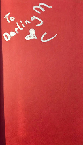 A red notebook or journal cover with white handwritten text reading 'To Darling M' and a heart, shown close up.