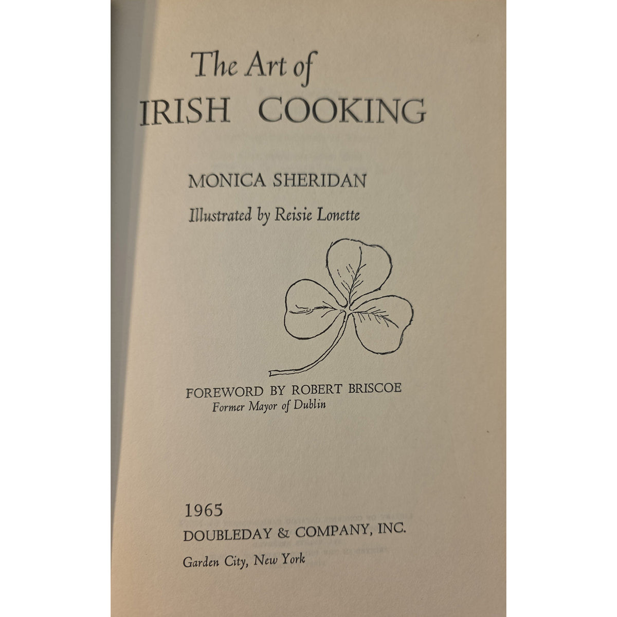The half title of the book 'The Art of Irish Cooking' by Monica Sheridan, published in 1965 by Doubleday & Company, Inc. The cover is a warm beige/cream color with black text and a simple line drawing of a shamrock.