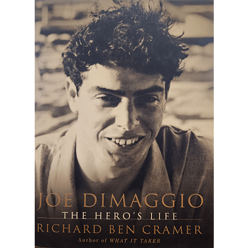 Cover image of Joe DiMaggio: The Hero's Life by Richard Ben Cramer. It features a sepia-toned photograph of a young Joe DiMaggio smiling, set against a blurred background, highlighting his natural charm.