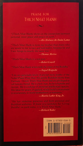 The back cover of a red book titled 'Praise for Thich Nhat Hanh' with printed review quotes, an ISBN barcode, and a small illustration of a lotus flower in the lower right corner.
