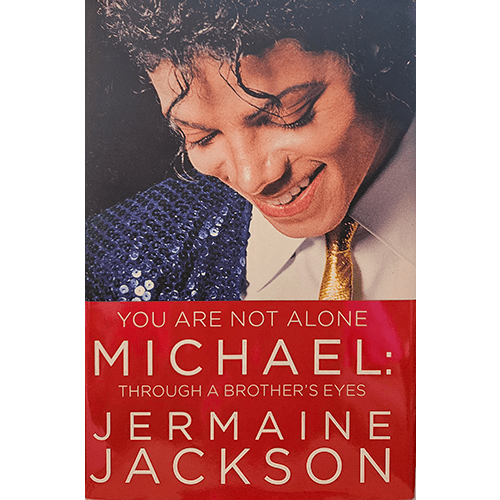 Cover of "You Are Not Alone: Michael, Through a Brother's Eyes" by Jermaine Jackson. Features a smiling Michael Jackson in a sequined outfit and golden tie, exuding charm and warmth.