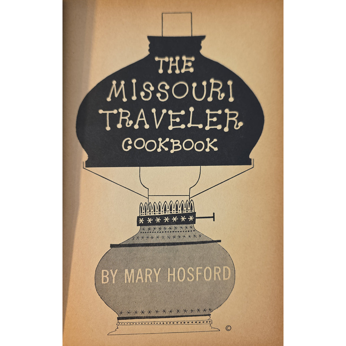 Vintage half title for 'The Missouri Traveler Cookbook' by Mary Hosford, featuring a large black oil lamp illustration on a warm tan background.
