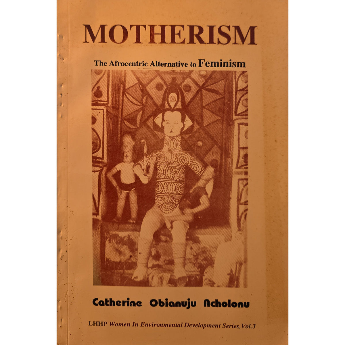 A book cover titled "MOTHERISM" with the subtitle "The Afrocentric Alternative to Feminism," featuring a sepia-toned illustration of figures and text at the bottom reading "Catherine Obianju Achonu.".