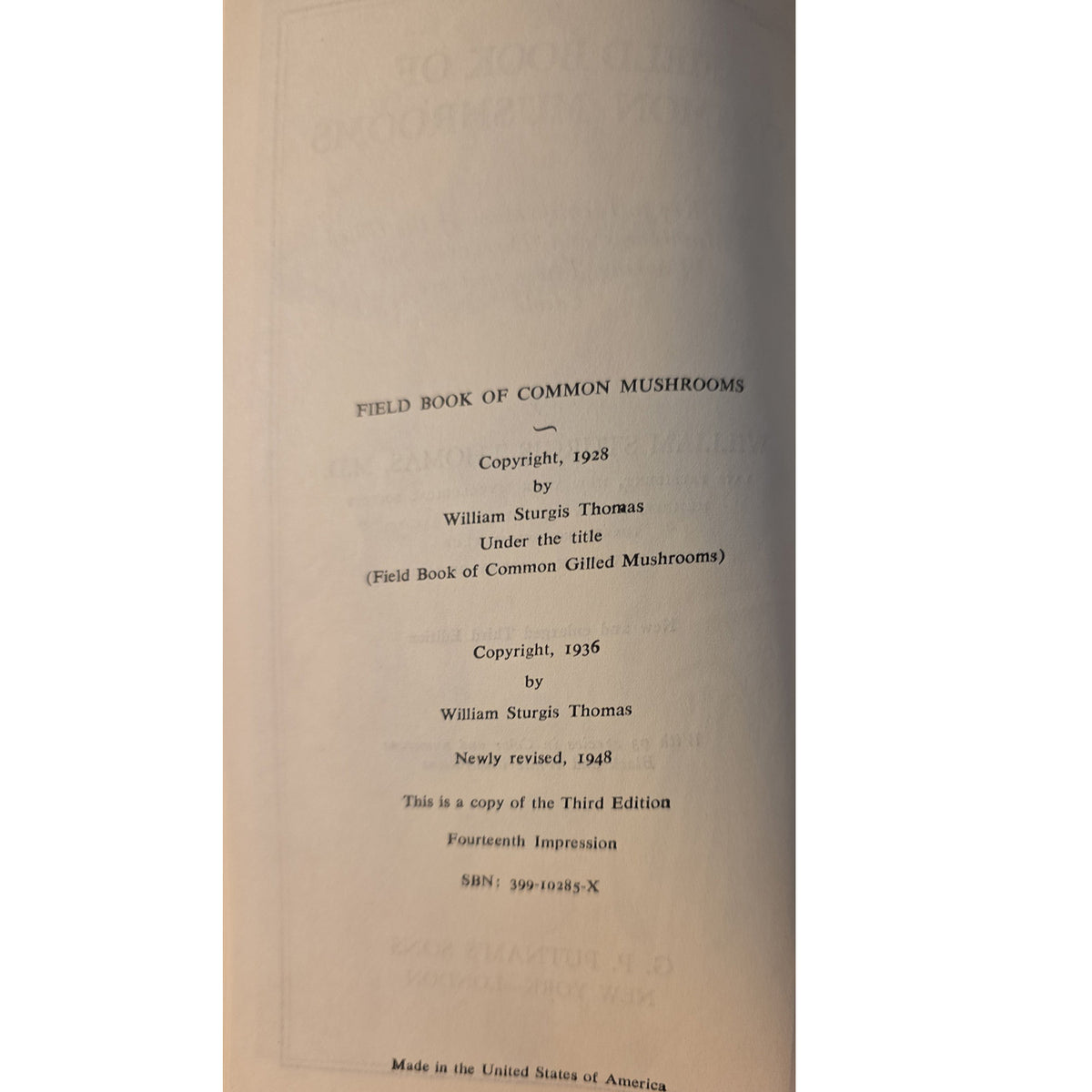 A close-up of a book's title page for 'Field Book of Common Mushrooms' by William Sturdi Thomas, showing copyright dates from 1928 and 1956 on aged, off-white paper.