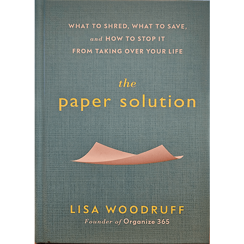 The cover of The Paper Solution by Lisa Woodruff features a minimalist design with soft blue textured background, showcasing a pink paper cutout at the bottom, reflecting simplicity in organization.