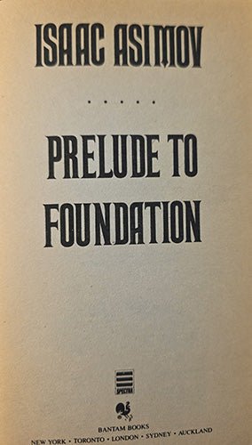 the half title page of the book 'Prelude to Foundation' by Isaac Asimov, published by Bantam Books. The cover features black serif typography on a warm, off-white background.