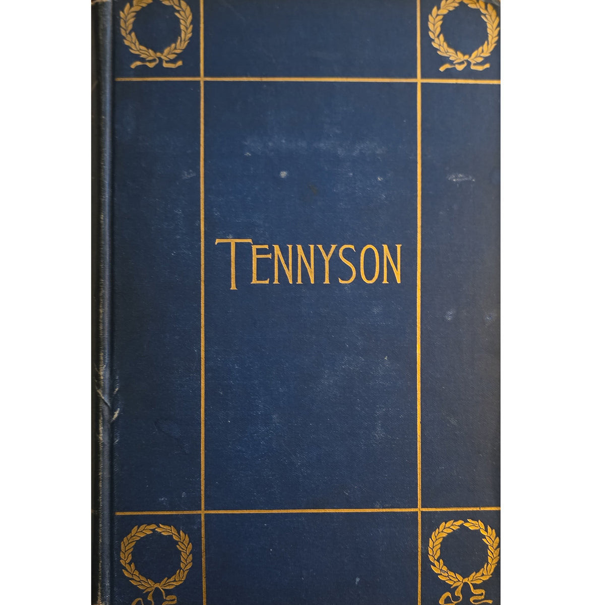 A vintage hardcover book with a dark blue cloth binding and gold foil detailing, featuring the name 'TENNYSON' in gold lettering in the center and laurel wreath motifs in the corners.