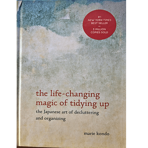 Cover of The Life-Changing Magic of Tidying Up by Marie Kondo, featuring a minimalist design with a faded watercolor-like background and bold red text, emphasizing simplicity and decluttering.