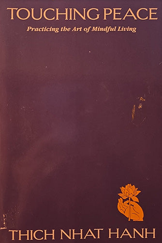 Book cover for 'Touching Peace: Practicing the Art of Mindful Living' by Thich Nhat Hanh, featuring a dark plum background with gold text and a small gold lotus hand illustration.