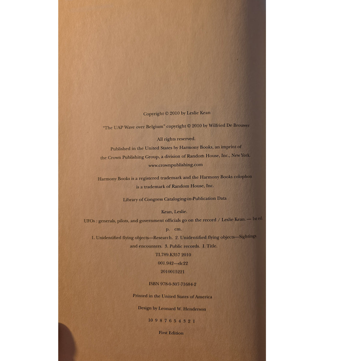  copyright and publication details in black text on a warm brown or tan background, photographed from above with a finger visible at the bottom left edge.
