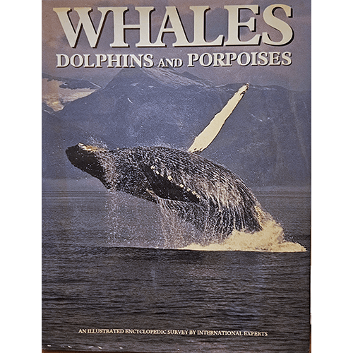 Cover of Whales, Dolphins and Porpoises, featuring a majestic whale breaching the ocean’s surface against a mountainous backdrop. The title is displayed in bold letters at the top of the cover.