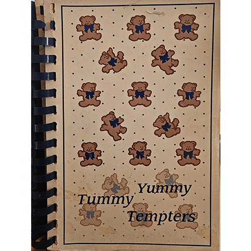 Cover of Tummy Yummy Tempters, a spiral-bound cookbook with dancing teddy bears on a white background, dotted with small blue spots, featuring family-friendly recipes, and signed by the author.